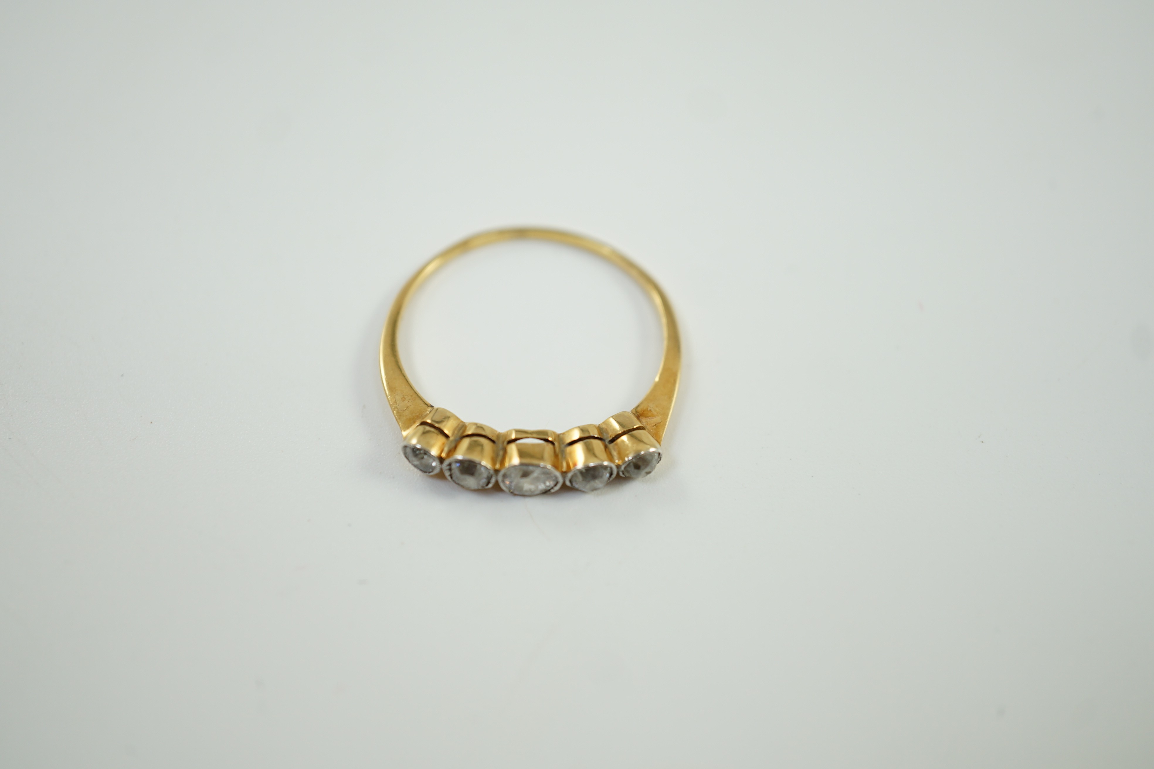 A yellow metal and graduated collet set five stone diamond half hoop ring, size V, gross weight 2.6 grams.
